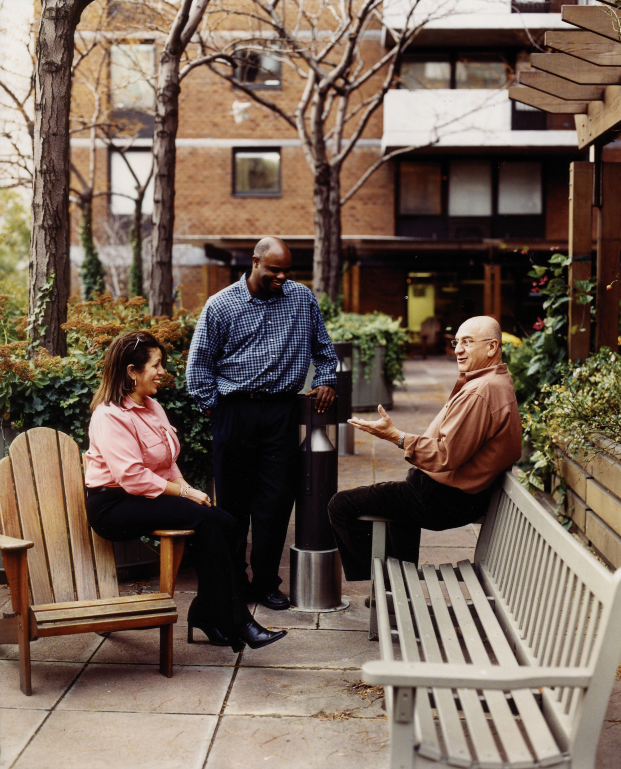 Three adults engaged in conversation in the Manhattan Plaza courtyard.